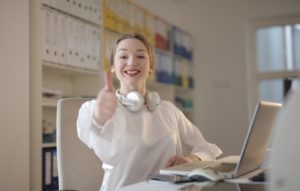 Woman sitting at desk giving thumbs up